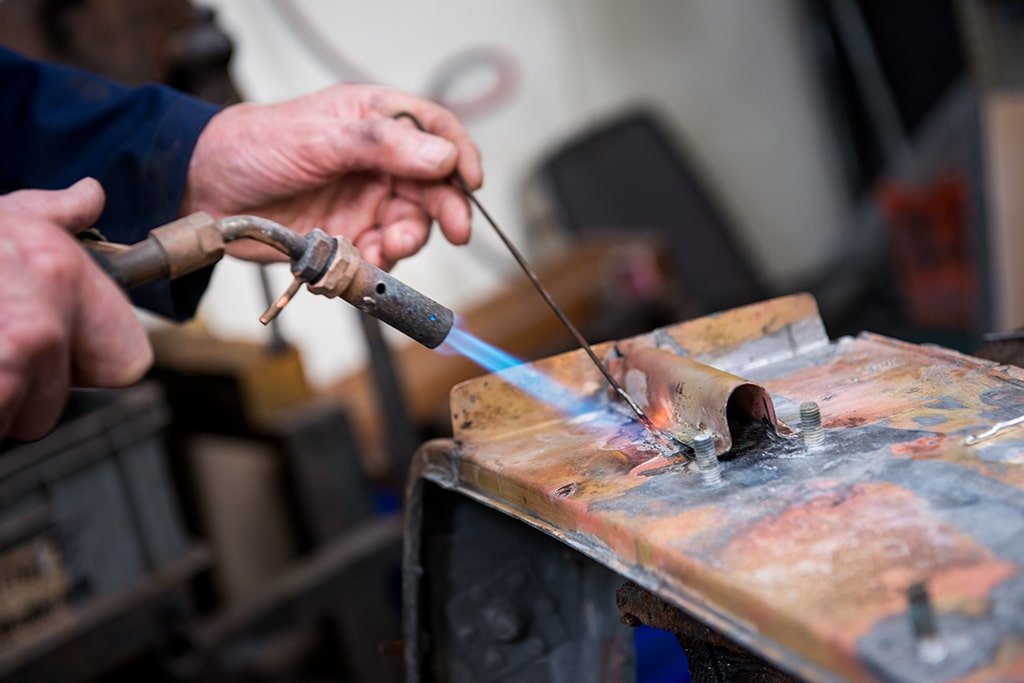 Man Working On Classic Car Part with Blowtorch