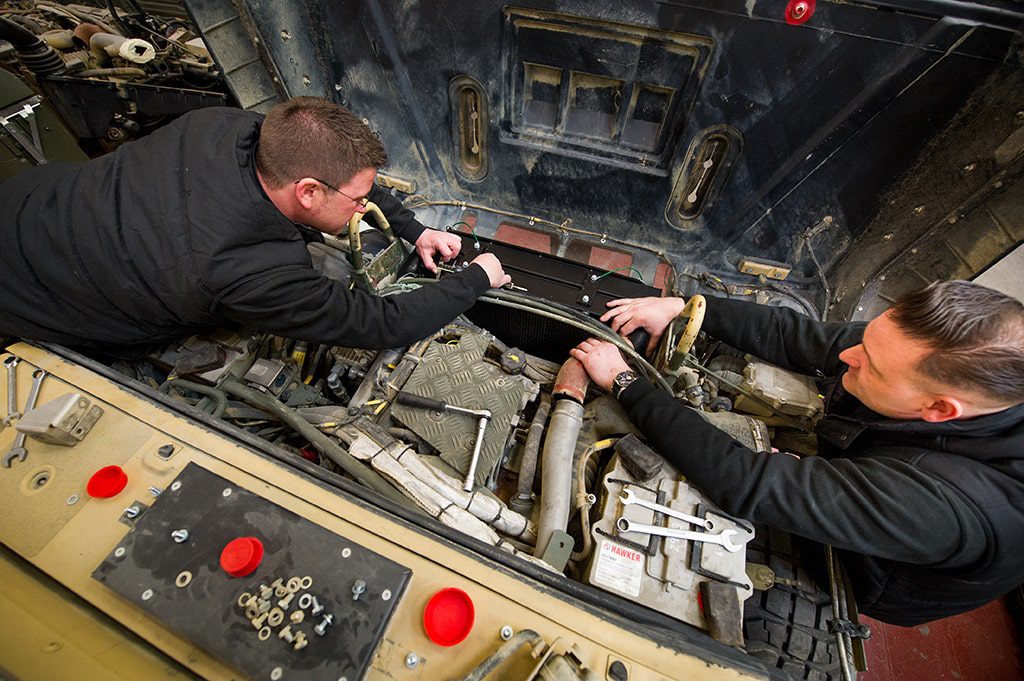 Top-Down View of Two Men Working on Exposed Vehicle Front Close Up